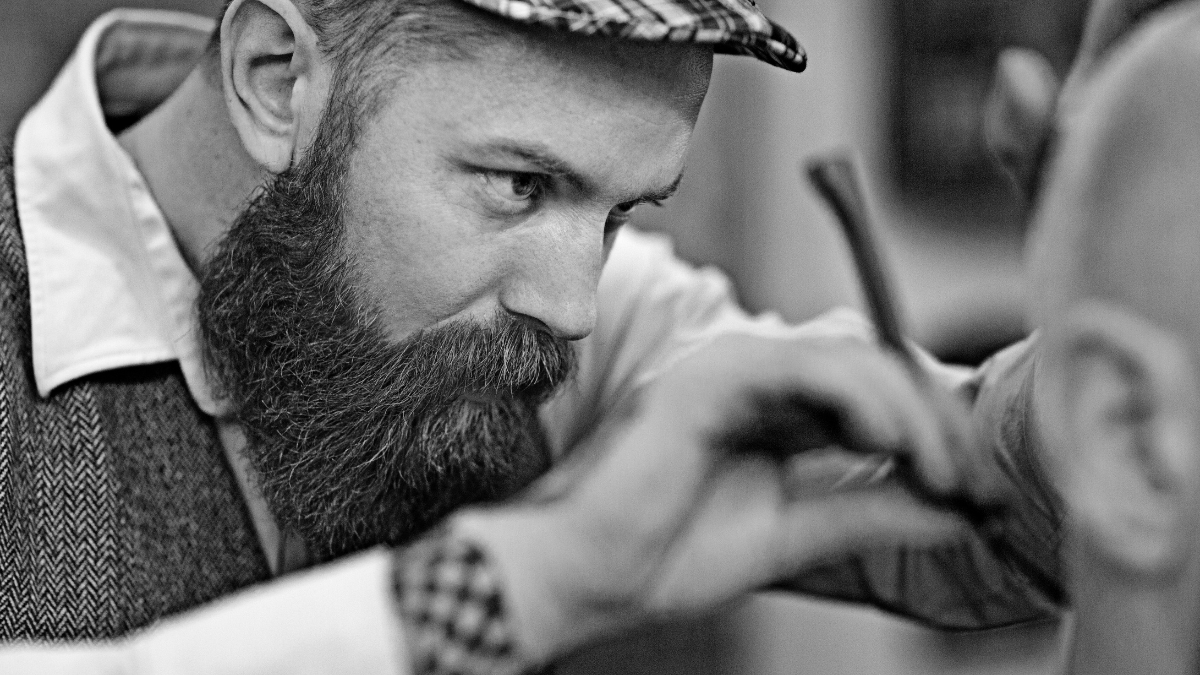 Парикмахер выполняет чистое бритье с помощью опасной бритвы с одним лезвием парикмахера на клиенте.